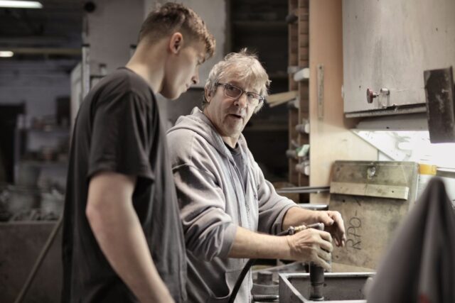 Experienced craftsperson guiding an apprentice with a pneumatic tool