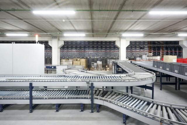 Conveyor belts winding through an industrial warehouse, illustrating flow through a production system.